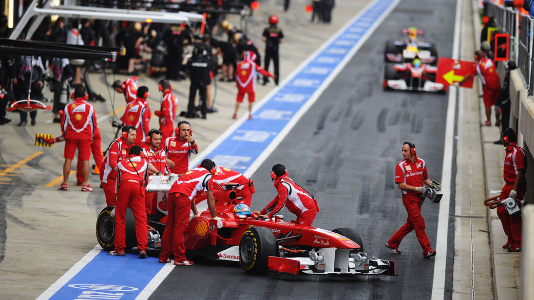 Carros da Ferrari retornam aos boxes durante o treino classificatório para o GP do Reino Unido, no circuito de Silverstone