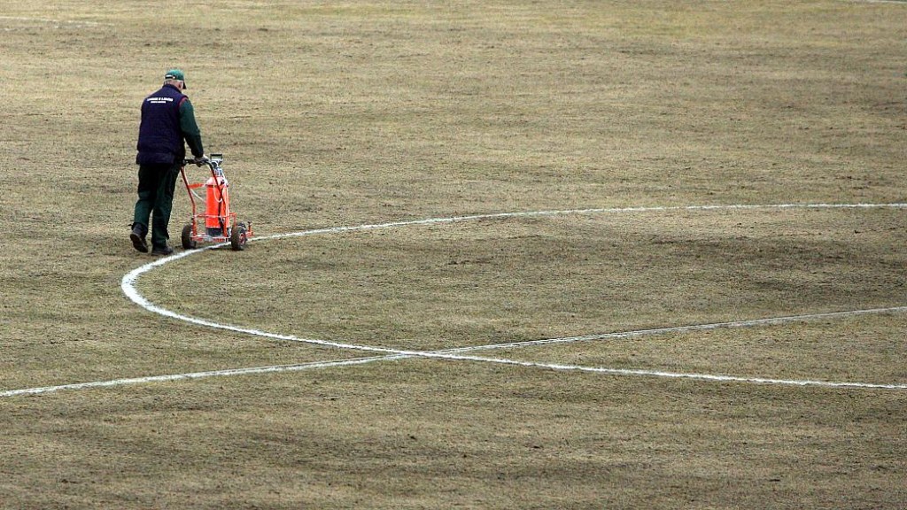 Funcionário marca as linhas do gramado do estádio em Kaunas. Campo esburacado e quase sem grama recebeu críticas