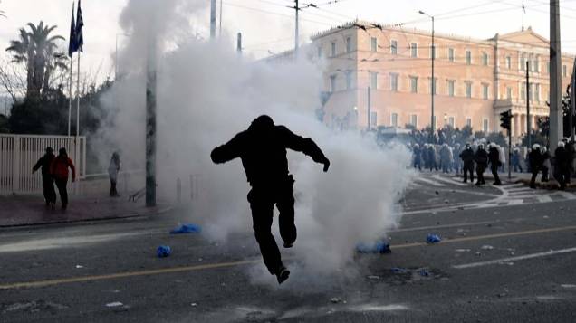 Manifestante chuta bomba de gás lacrimogêneo em confronto com a polícia em frente ao Parlamento grego, 12/02/2012