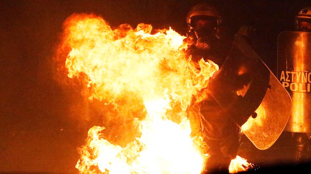 Policial é atingido por chamas de uma bomba de gasolina jogada por manifestantes em frente ao parlamento, durante confrontos em Atenas, na Grécia, em 07/11/2012