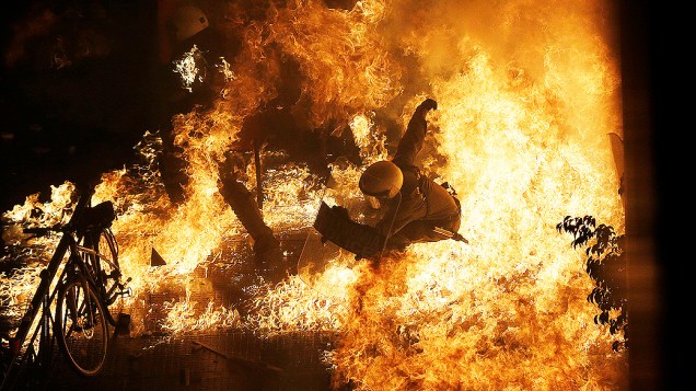 Policial é atingido por chamas de uma bomba de gasolina jogada por manifestantes em frente ao parlamento, durante confrontos em Atenas, na Grécia