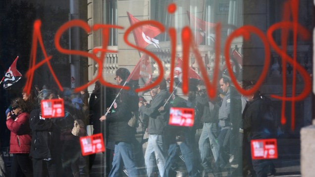 Manifestantes fazem pichação na porta de uma agência bancária em Madri durante a greve geral na Espanha