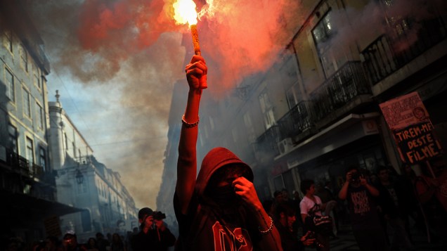 Manifestante segura tocha pelas ruas de Lisboa durante a greve geral em Portugal