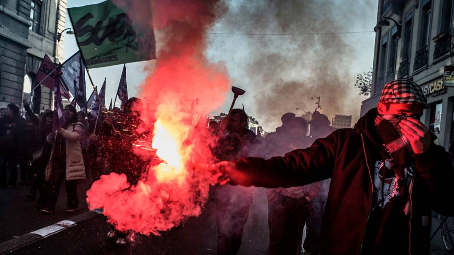 Manifestante segura tocha pelas ruas de Lyon durante a greve geral na França
