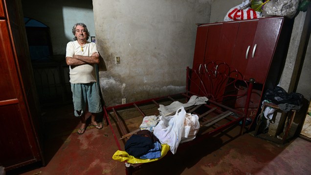 A invasão de água e de esgoto destruiu móveis na casa da doméstica Raimunda. O vizinho Paulo Sérgio ajudou na retirada de poucos objetos da família