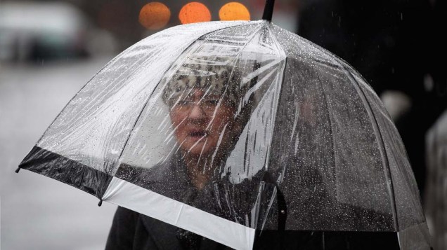 Mulher caminha sob chuva em Londres, Inglaterra