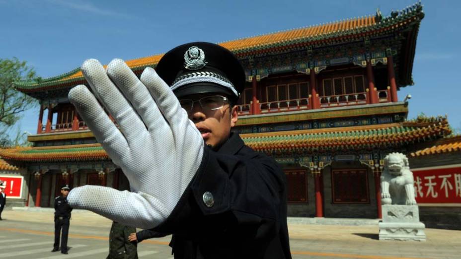 Policial impede fotógrafos na sede central do Partido Comunista da China, após a demissão do político Bo Xilai
