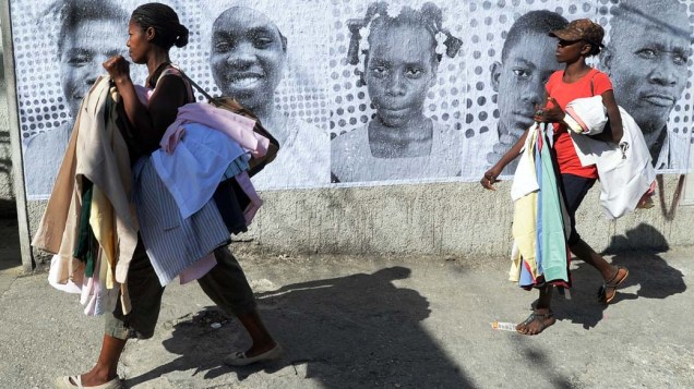 Haitianas andam em frente a posters das vítimas do terremoto em Porto Princípe, em 10 de janeiro de 2012