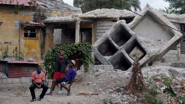 Pessoas sentadas em destroços de casas destruídas pelo terremorto em Porto Princípe no Haiti, em 03 de janeiro de 2012
