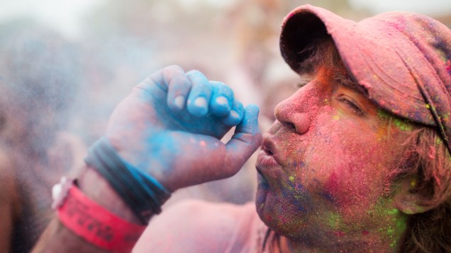 Homem sopra o pó colorido no ar durante o Festival de Holi, em Berlim, Alemanha