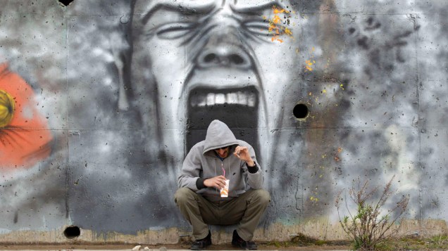 Homem toma café em frente a um mural, próximo à cidade costeira de Kalamatta região de Messinia, Grécia