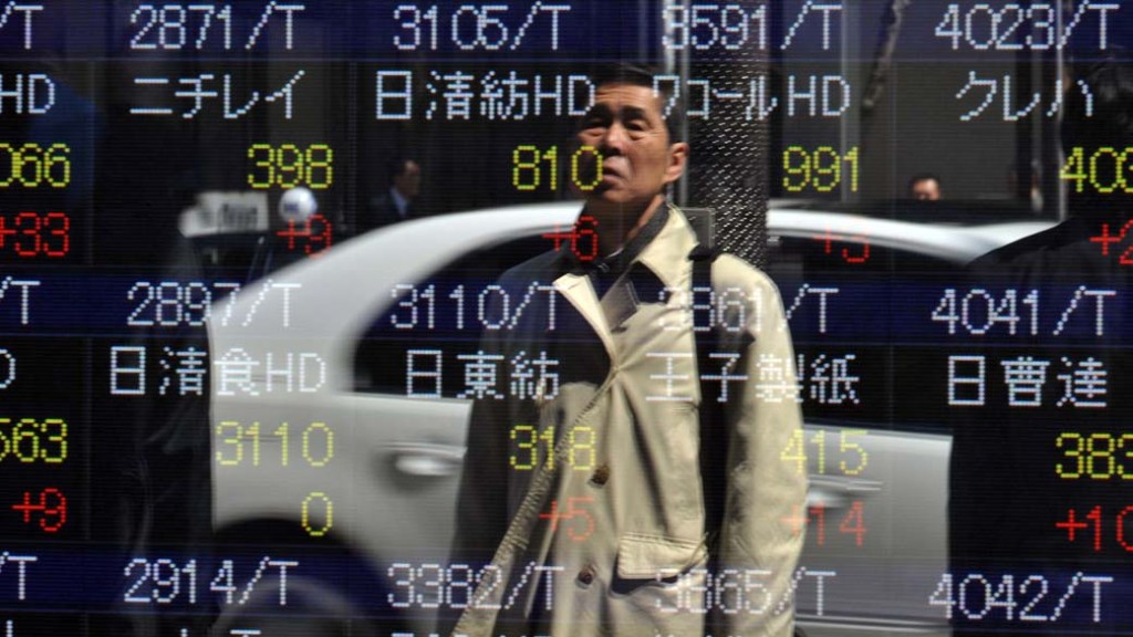 Reflexo de pedestre em painel de cotações da bolsa em Tóquio, Japão