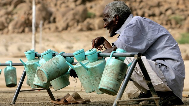 Homem sudanês usa um balde de água para lavar as mãos em campo de refugiados no Estado de Kassala, no leste do Sudão