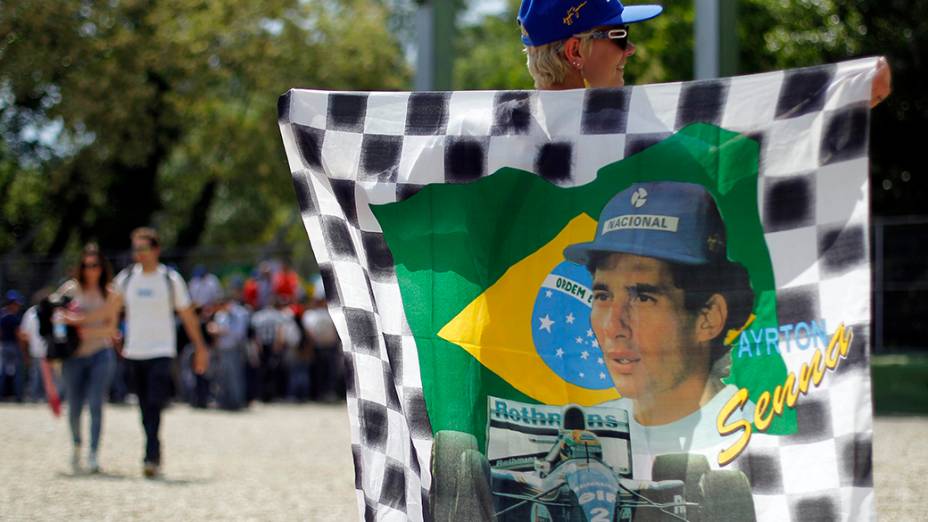 Mulher carrega bandeira em homenagem a Ayrton Senna na pista de corrida em Imola, na Itália