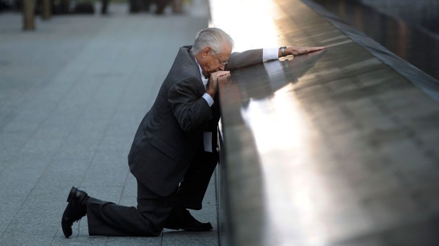 Robert Peraza ajoelha em frente ao nome do filho, Robert David Peraza, uma das vítimas do 11 de Setembro, em Nova York