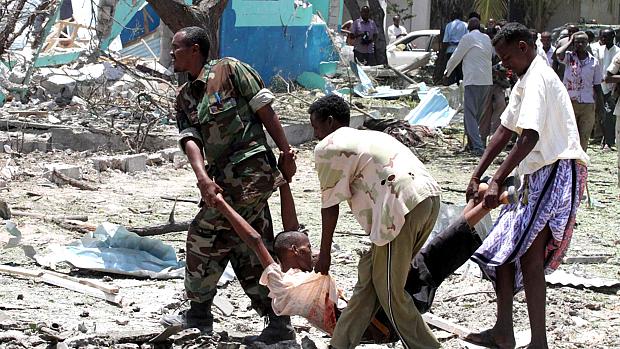 Homens carregam uma das vítimas do atentado em Mogadíscio