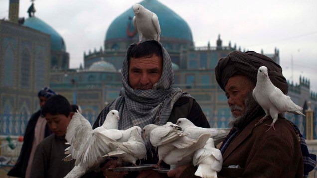 Homens alimentam pombas em frente a Mesquita Azul na cidade de Mazaru Sharif, Afeganistão