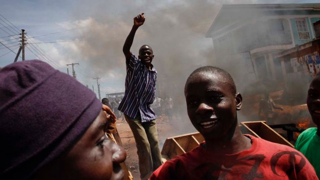 Ugandenses em barricada durante protesto contra a prisão do líder da oposição, Kizza Besigye, no subúrbio da capital Campala