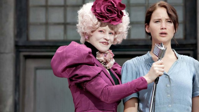 A extravagante Effie Trinket (Elizabeth Banks) é responsável por fazer com que todos os tributos, como Katniss Everdeen (Jennifer Lawrence), compareçam aos compromissos dos Jogos Vorazes