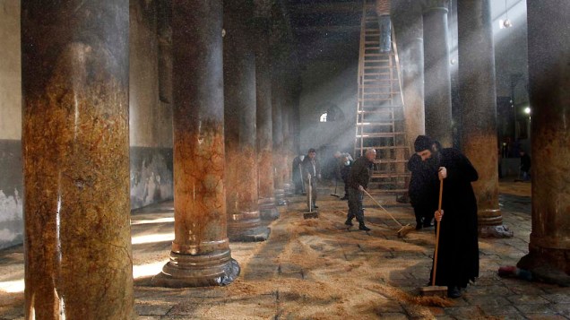 Grego ortodoxo e clérigo armênio limpam a Igreja da Natividade em Belém, Cisjôrdania