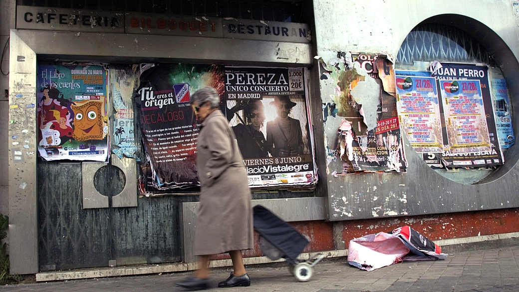 Mulher com seu carrinho de compras caminha em rua de Madri