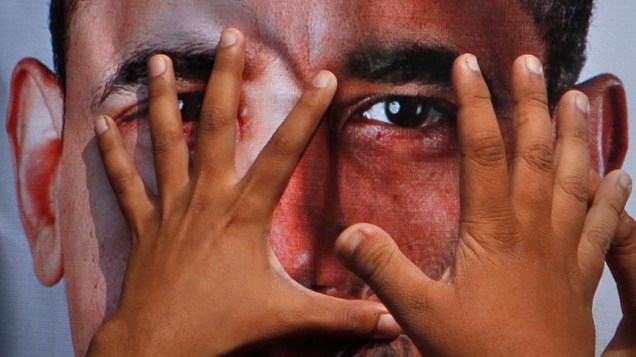 Imagem de Barack Obama coberta pelas mãos de partidários do movimento anti-americano em Hyderabad, no Paquistão