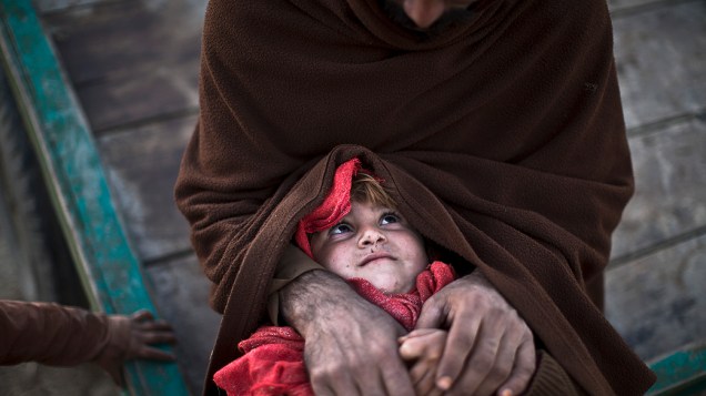 Nazko Pahalwan, de 3 anos, que foi deslocada devido os combates entre os talibãs e o exército, no colo de seu pai, em um bairro pobre na periferia de Islamabad, Paquistão