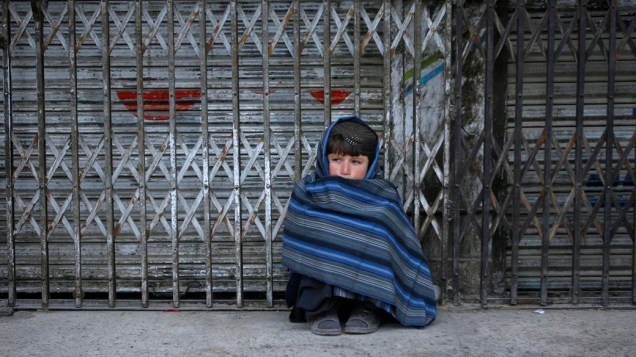 No Paquistão, menino aguarda abertura de mercado em que trabalha
