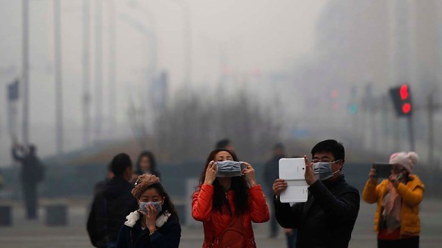 Jovem coloca máscara para se proteger da poluição em Shijiazhuang, capital da província de Hebei, norte da China, nesta terça-feira (25). Várias cidades estão em estado de alerta desde sexta (21), quando foram cobertas por uma densa camada cinzenta