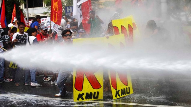 Manifestantes são atingidos por jatos de água durante confronto com policiais em Manila, nas Filipinas, nesta terça-feira (25)