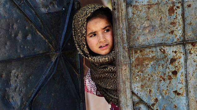 Menina afegã é fotografada na porta de sua escola em um campo de refugiados em Haripur, nesta terça-feira (25)