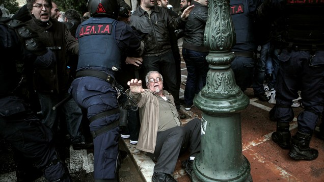 Em Atenas, idoso cai no chão em confrontro com a polícia durante uma manifestação contra as medidas de austeridade na Grécia