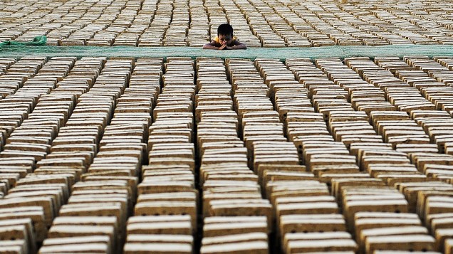 Criança olha para fábrica de tijolos, em Mianmar