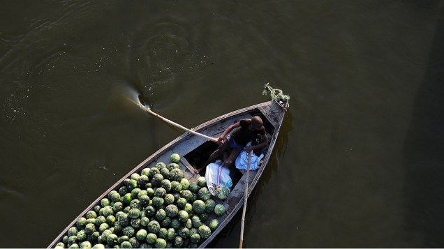 Trabalhador transporta abóboras em um barco na cidade de Allahabad, Índia