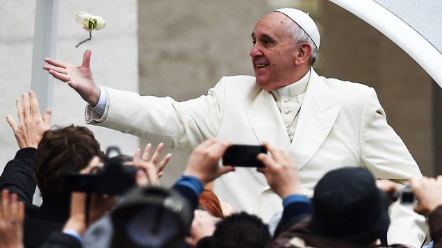 Papa Francisco tenta pegar rosa branca lançada por um peregrino ao chegar para a audiência geral na praça de São Pedro, no Vaticano, nesta quarta-feira (26)