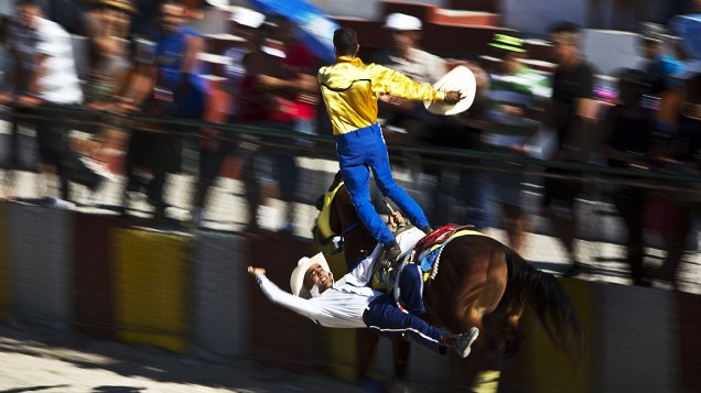 Fotografia divulgada nesta quarta-feira (26) mostra dois peões se aventurando com um cavalo durante rodeio realizado no final de semana em Havana, Cuba