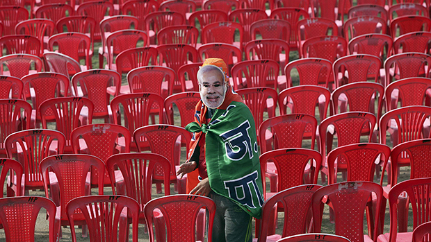 Homem com máscara do primeiro-ministro da Índia Narendra Modi antes de um comício eleitoral do candidato em Hiranagar, na Índia