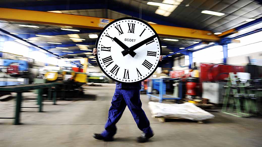 Empregado carrega relógio em fábrica, na França