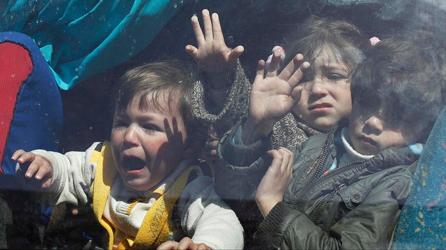 Crianças palestinas esperam para cruzar para o Egito na fronteira entre de Rafah e o sul da Faixa de Gaza