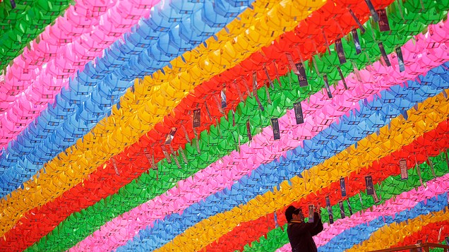 Homem amarra pedidos de oração, com nomes escritos em cartões, em lanternas de lótus, na preparação para o próximo aniversário de Buda no templo Jogye em Seul, Coreia do Sul