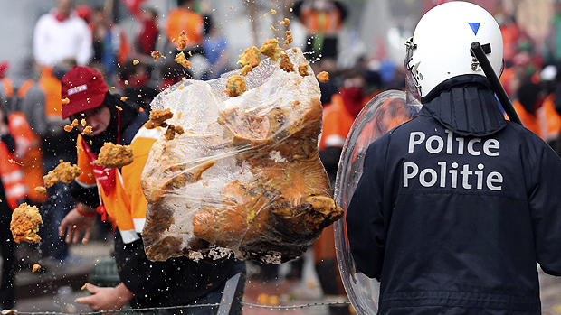 Manifestante atira saco cheio de lixo em policial durante manifestação em Bruxelas, na Bélgica, nesta sexta-feira (04)