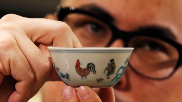 Nicolas Chow, Diretor da casa de leilões Sotheby’s Ásia, mostra pequena porcelana da dinastia Ming do século 15 chamada de Copo da galinha foi vendida por mais de 36 milhões de dólares durante leilão em Hong Kong, batendo o recorde de valor mais alto pago por uma porcelana chinesa