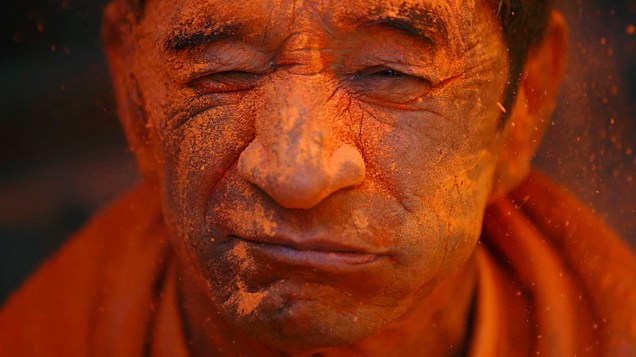 Devoto com o rosto pintado com pó vermelho participa do festival Sindoor Jatra  na cidade de Thimi, perto de Katmandu, no Nepal