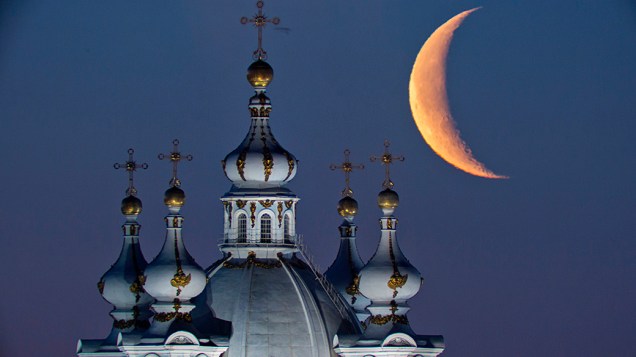 A lua vista acima das cúpulas da Catedral Smolny em São Petersburgo, na Rússia