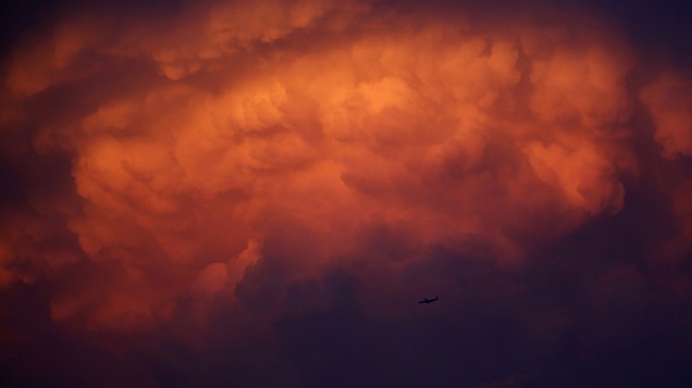 Avião fotografado sob uma nuvem de tempestade ao amanhecer em Bangcoc, na Tailândia