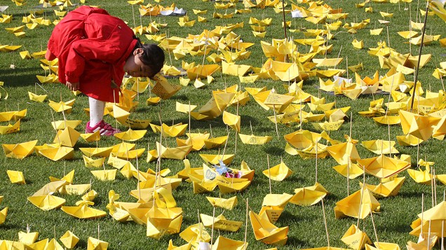 Menina lê mensagens escritas em barquinhos de papel homenageando as vítimas do naufrágio da balsa Sewol em um memorial na cidade de Seul, na Coreia do Sul