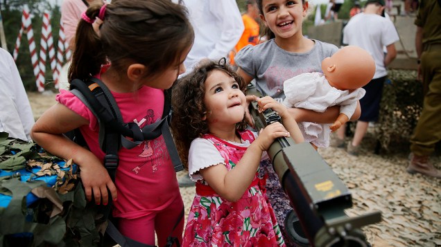 Criança israelense brinca com arma durante uma exibição para marcar o 66º aniversário da independência de Israel, no assentamento de Efrat, na Cisjordânia