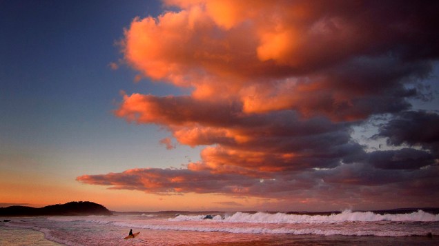 Surfista segura sua prancha durante o por-do-sol em Mollymook Beach, na Austrália