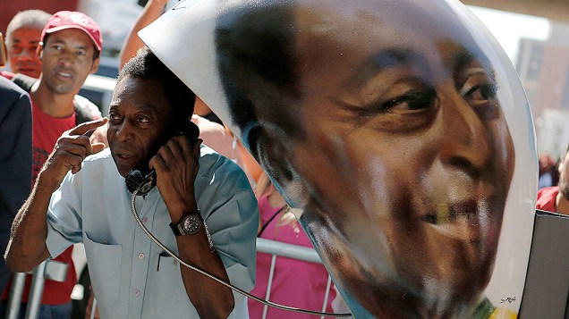 Pelé posa ao lado de um orelhão com seu rosto pintado pelo artista brasileiro Sipros, em São Paulo