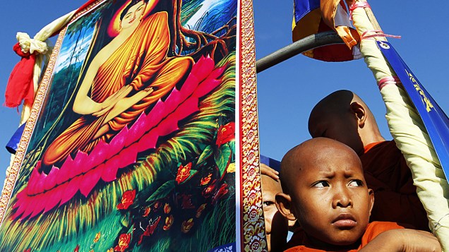 No Camboja, monges posam ao lado da imagem do Buda durante as celebrações que comemoram a iluminação e a passagem ao nirvana